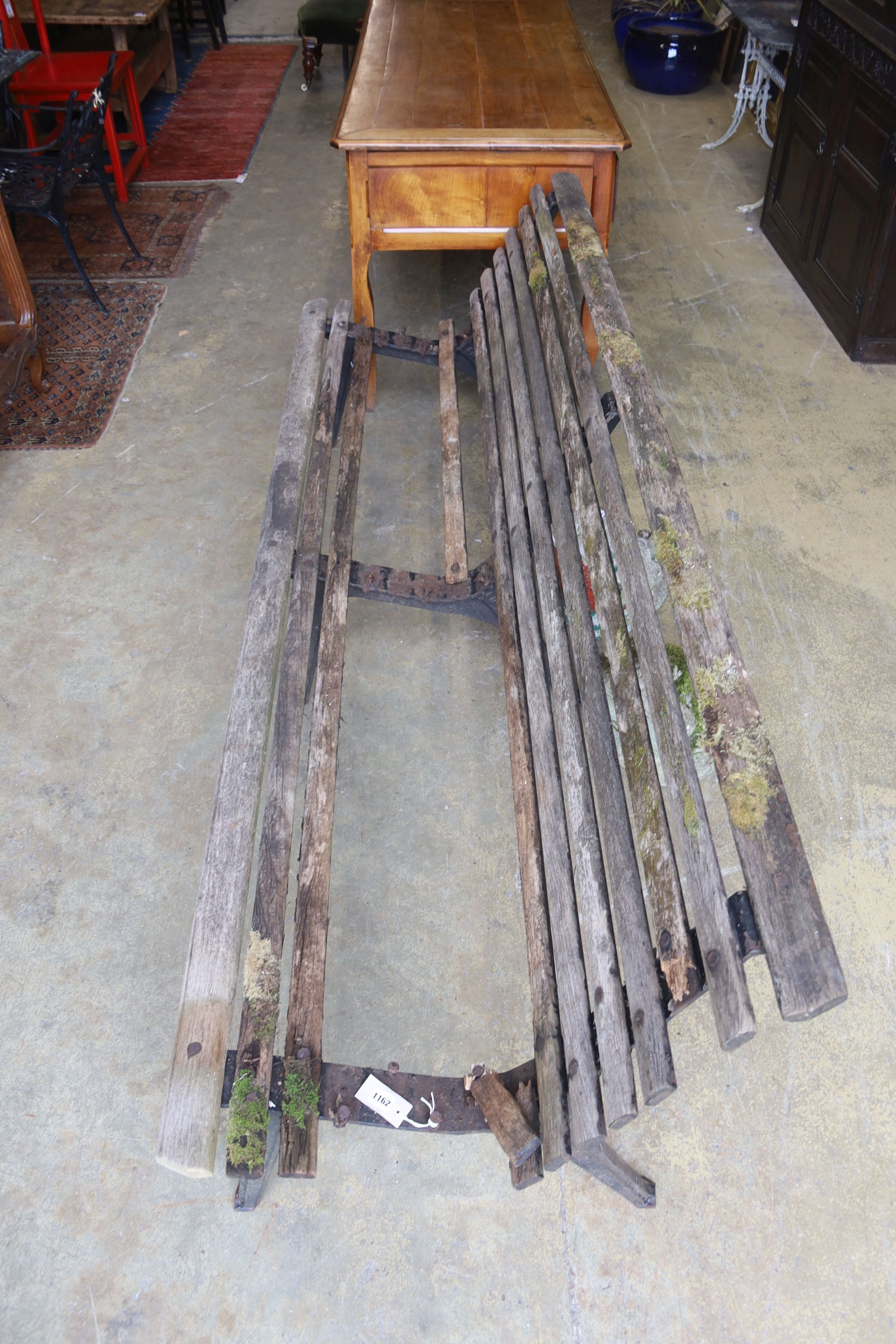 A slatted wood garden bench marked L M Furniture (in need of repair), length 244cm, depth 70cm, height 77cm